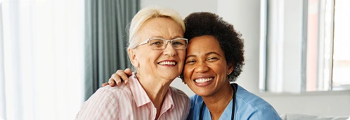 Caregiver and older woman smiling together, showing warmth and companionship at home.