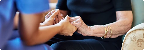 Caregiver holding an elderly person’s hands, providing reassurance and attentive support.