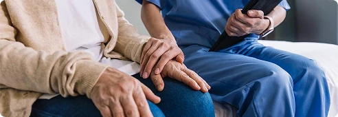 Caregiver gently holding an elderly person’s hands, offering comfort and emotional support.