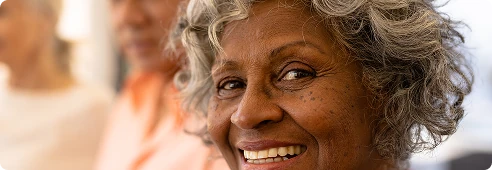 Close-up of an older woman smiling, conveying comfort and reassurance during care.